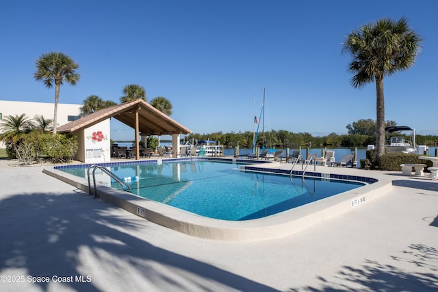 view of swimming pool with a patio area and a water view