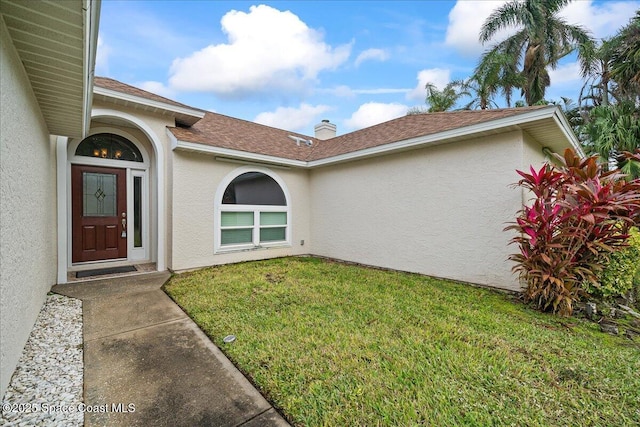 view of exterior entry with a lawn