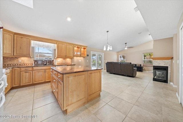 kitchen with a healthy amount of sunlight, pendant lighting, a multi sided fireplace, and lofted ceiling