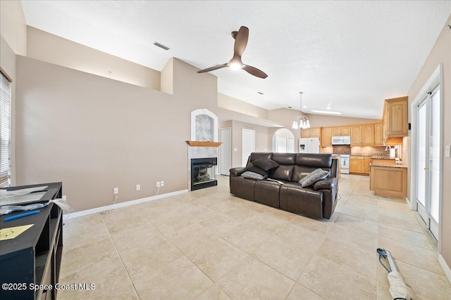 living room featuring ceiling fan with notable chandelier, light tile patterned floors, and vaulted ceiling