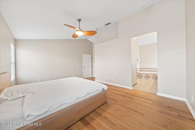 bedroom with vaulted ceiling, ceiling fan, light hardwood / wood-style flooring, and connected bathroom