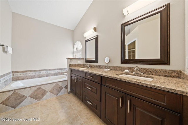 bathroom with vanity, tiled tub, and vaulted ceiling