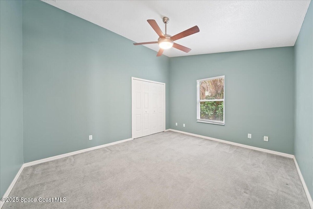 spare room featuring lofted ceiling, light carpet, and ceiling fan