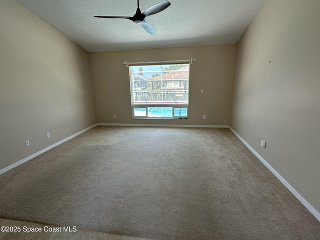 empty room featuring a ceiling fan, baseboards, a textured ceiling, and carpet floors