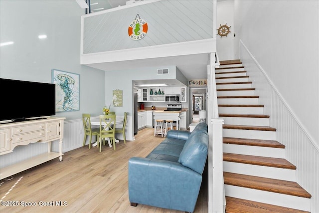 living room with a towering ceiling and light wood-type flooring