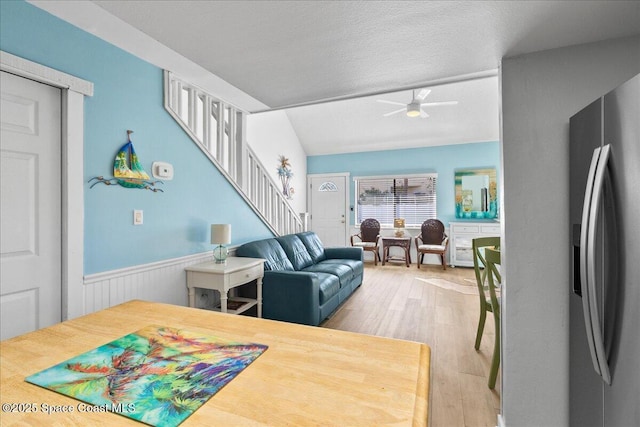 living room with a textured ceiling, ceiling fan, and light hardwood / wood-style floors