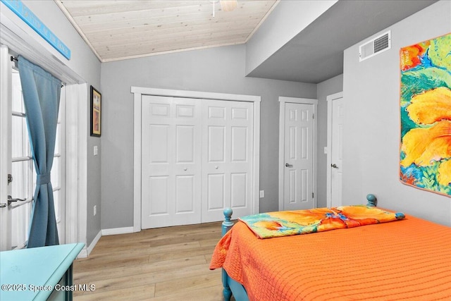 bedroom featuring vaulted ceiling, wood ceiling, light hardwood / wood-style flooring, a closet, and crown molding