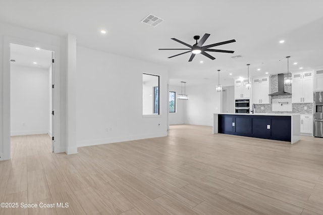 unfurnished living room with ceiling fan and light hardwood / wood-style floors