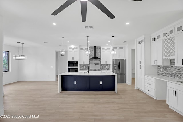 kitchen with wall chimney range hood, decorative light fixtures, and stainless steel refrigerator with ice dispenser