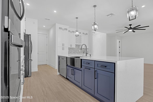 kitchen featuring white cabinetry, pendant lighting, an island with sink, and appliances with stainless steel finishes