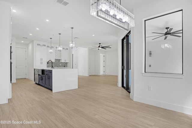 kitchen with pendant lighting, white cabinets, ceiling fan, and light hardwood / wood-style flooring