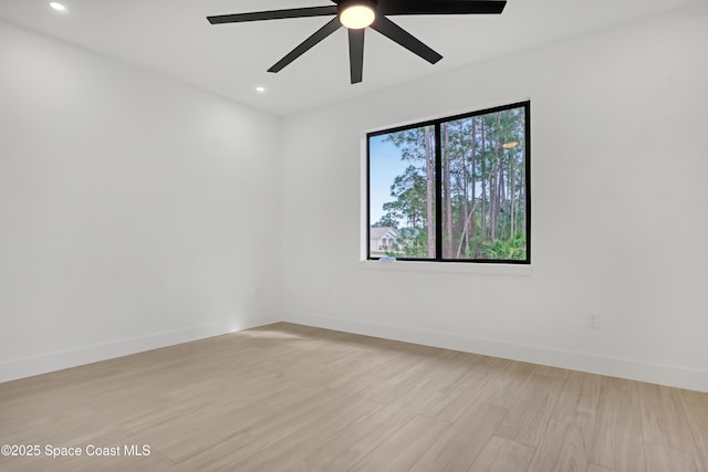 empty room with ceiling fan and light hardwood / wood-style flooring