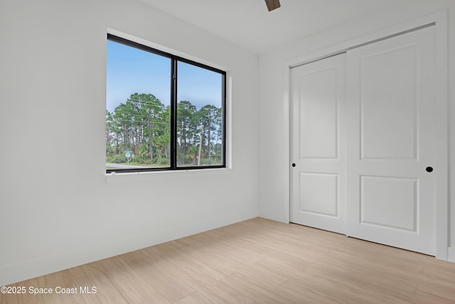 unfurnished bedroom with a closet, ceiling fan, and light hardwood / wood-style flooring