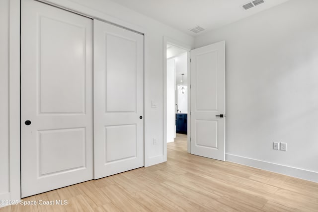 unfurnished bedroom featuring a closet and light wood-type flooring