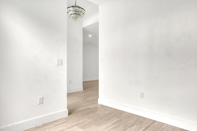 empty room featuring an inviting chandelier and light hardwood / wood-style floors