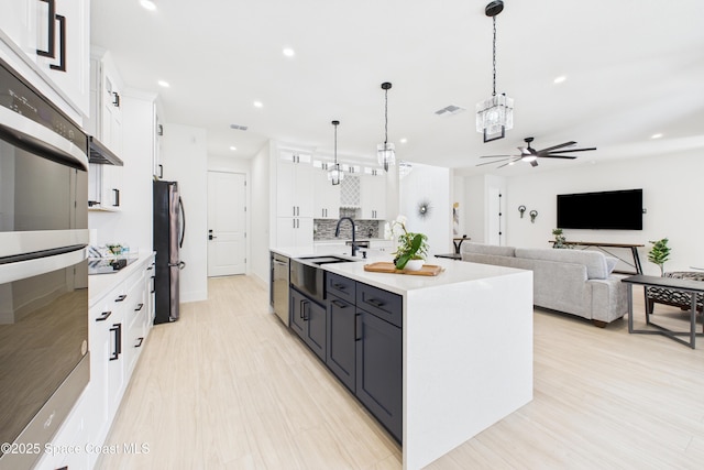 2311 San Filippo Dr SE, Palm Bay, FL 32909 - kitchen with white cabinets, light countertops, a center island with sink, appliances with stainless steel finishes, and ceiling fan with notable chandelier