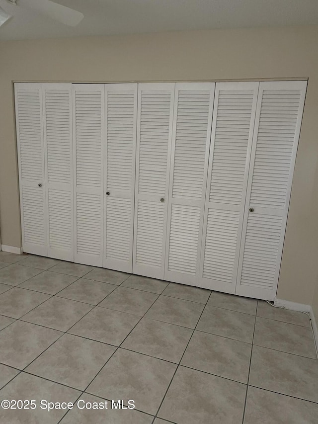 unfurnished bedroom with a closet, light tile patterned floors, and ceiling fan