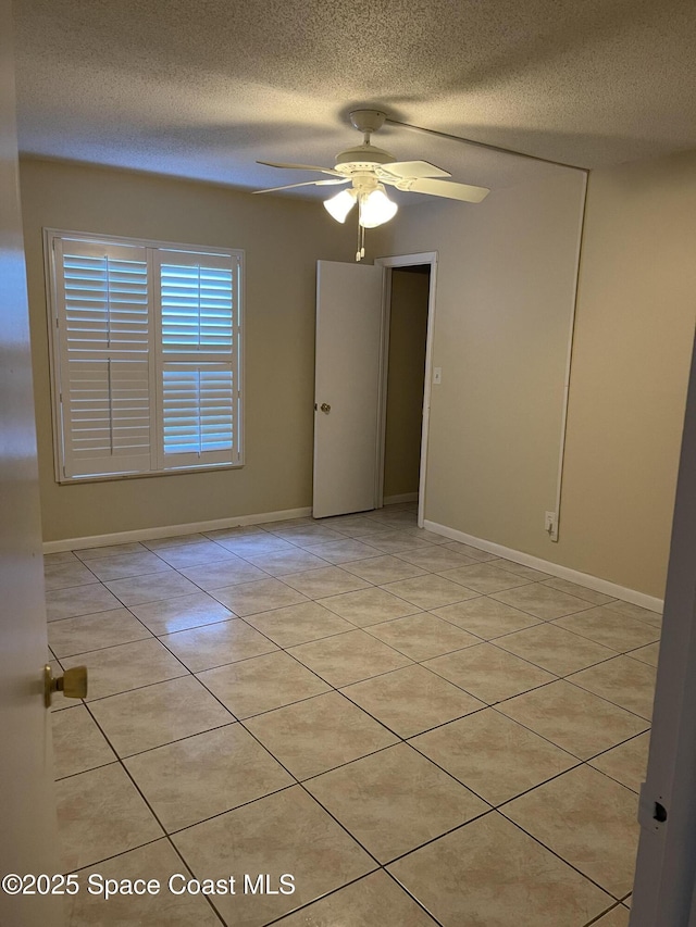 tiled empty room with ceiling fan and a textured ceiling