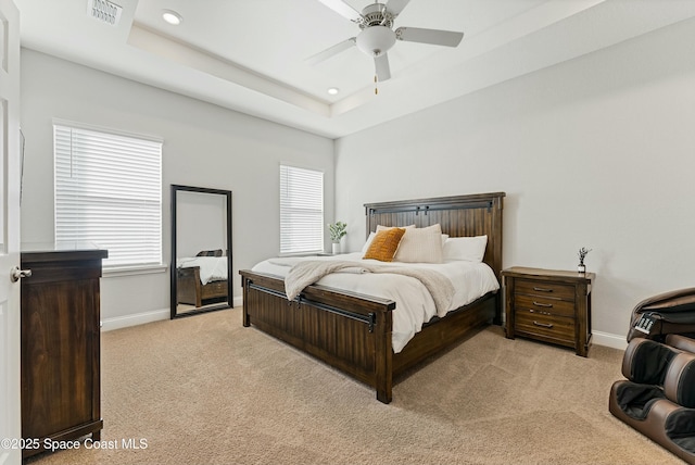 bedroom featuring light colored carpet, ceiling fan, and a tray ceiling