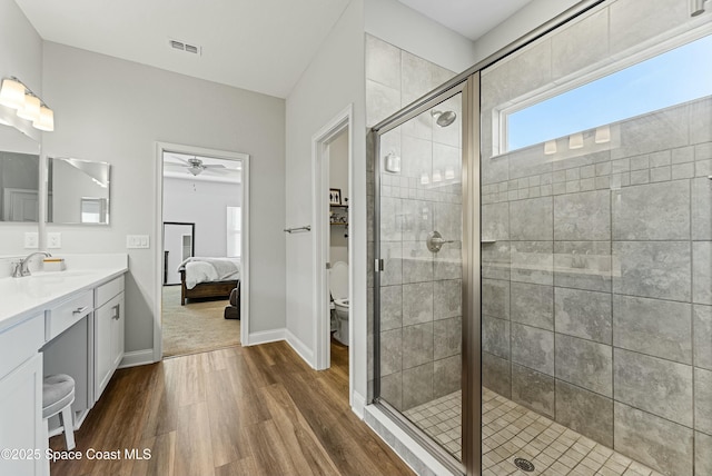 bathroom featuring toilet, vanity, ceiling fan, and walk in shower