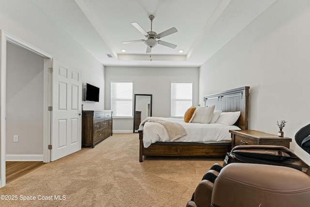 carpeted bedroom featuring ceiling fan and a raised ceiling