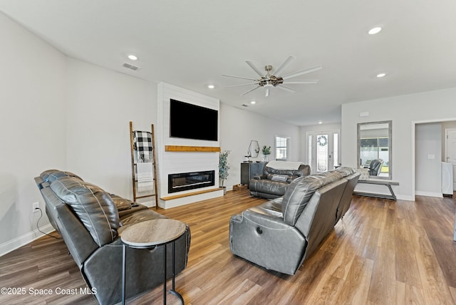 living room featuring wood-type flooring, a fireplace, and ceiling fan