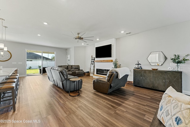 living room featuring wood-type flooring, a fireplace, and ceiling fan