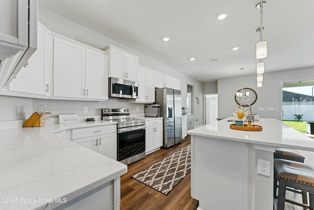 kitchen with white cabinets, stainless steel appliances, sink, and hanging light fixtures