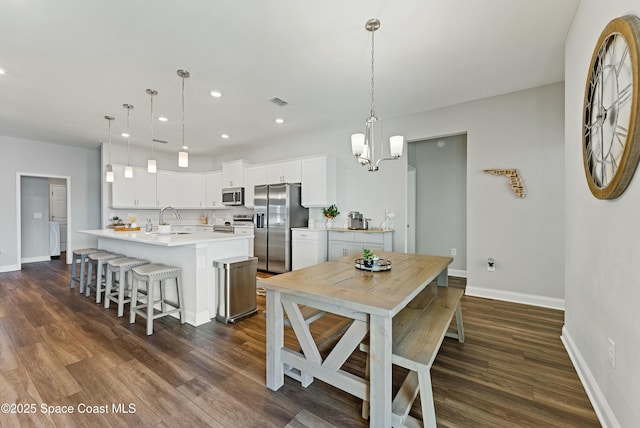 dining area with sink, dark hardwood / wood-style flooring, and a chandelier