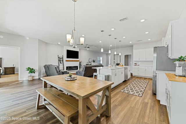 dining area with ceiling fan, light hardwood / wood-style floors, and sink