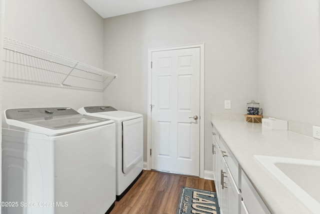 laundry area with sink, dark hardwood / wood-style flooring, separate washer and dryer, and cabinets