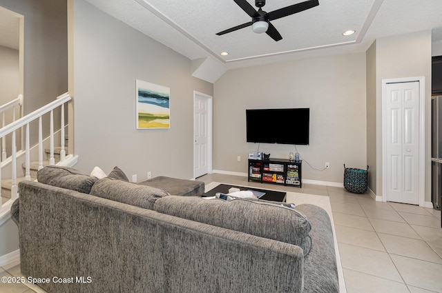 tiled living room featuring lofted ceiling, ceiling fan, and a textured ceiling