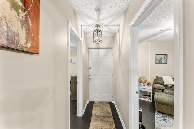 doorway to outside featuring a textured ceiling and dark wood-type flooring