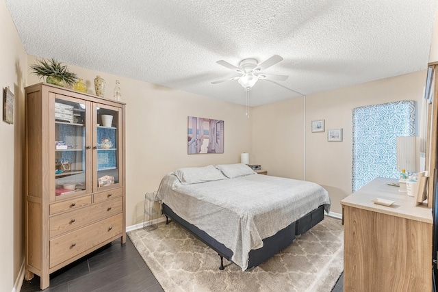 bedroom with dark wood-type flooring, a textured ceiling, and ceiling fan