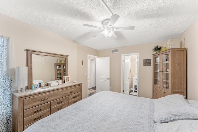 bedroom with a textured ceiling, ceiling fan, and connected bathroom