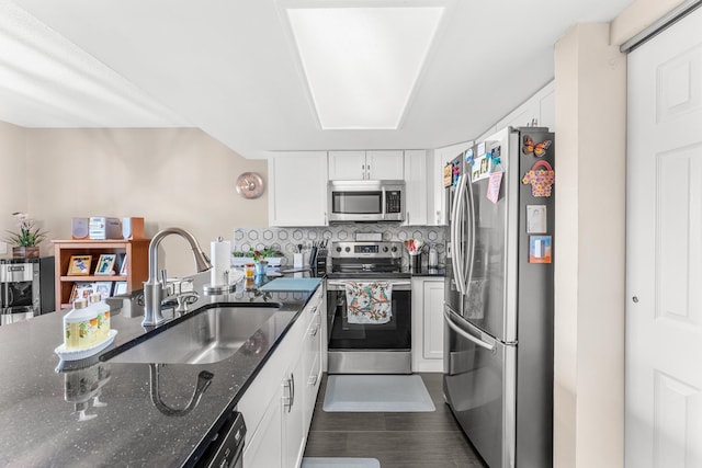 kitchen featuring dark stone counters, stainless steel appliances, white cabinets, and sink