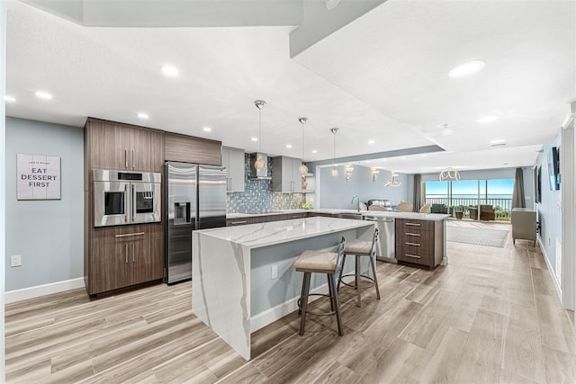 kitchen with a kitchen bar, stainless steel appliances, tasteful backsplash, a kitchen island, and pendant lighting