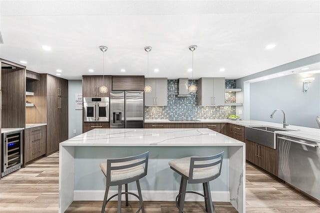 kitchen with a spacious island, beverage cooler, hanging light fixtures, and stainless steel appliances