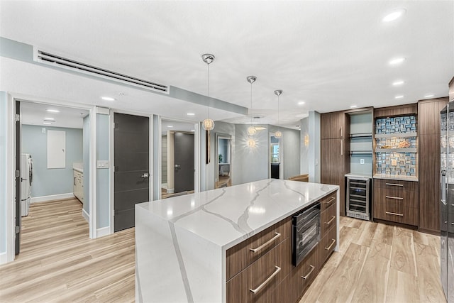 kitchen featuring decorative light fixtures, wine cooler, a large island, light hardwood / wood-style flooring, and built in microwave