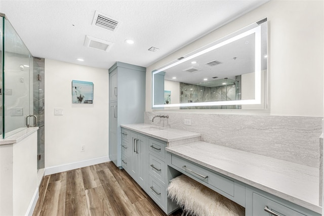 bathroom with hardwood / wood-style floors, an enclosed shower, a textured ceiling, vanity, and tasteful backsplash