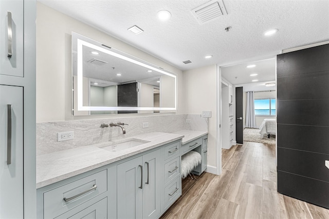 bathroom featuring vanity, decorative backsplash, a textured ceiling, and hardwood / wood-style floors