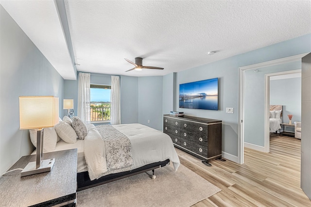 bedroom with a textured ceiling, ceiling fan, and light wood-type flooring