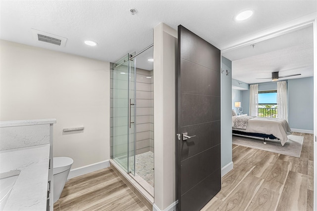 bathroom with a textured ceiling, ceiling fan, hardwood / wood-style floors, and an enclosed shower