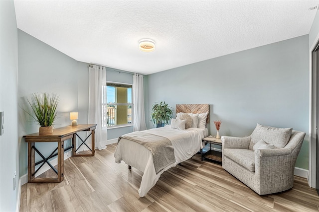 bedroom featuring a textured ceiling and light hardwood / wood-style flooring