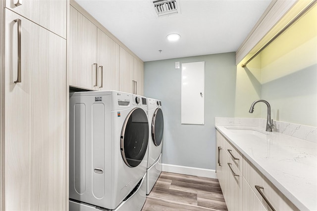 washroom with light wood-type flooring, cabinets, independent washer and dryer, and sink