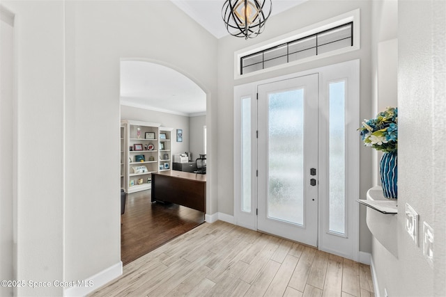 foyer with ornamental molding and a chandelier