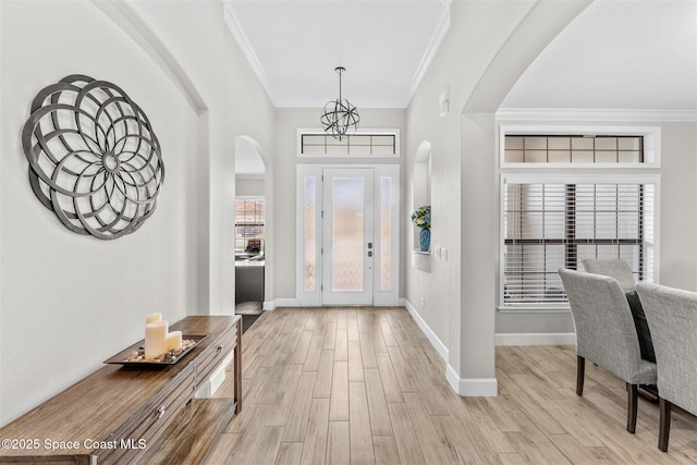 entryway with light hardwood / wood-style floors, crown molding, and an inviting chandelier