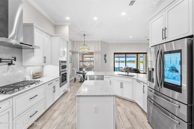 kitchen with sink, white cabinets, wall chimney range hood, and appliances with stainless steel finishes