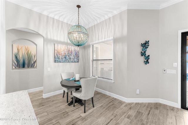 dining space featuring an inviting chandelier, light hardwood / wood-style flooring, and ornamental molding