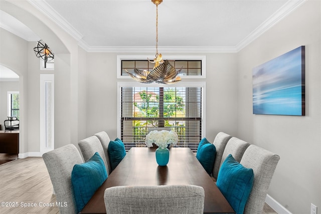 dining space featuring a notable chandelier, light hardwood / wood-style flooring, and ornamental molding